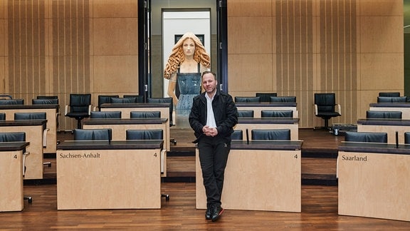 Der Bildhauer und Landeskunstpreisträger Marc Fromm steht vor seiner Holzskulptur «Die Laborantin» im Plenarsaal des Bundesrates.