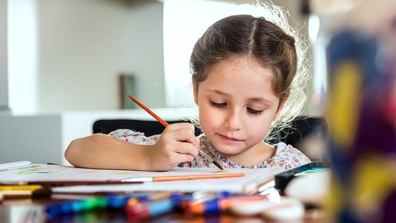 Ein Mädchen malt mit einem Pinsel