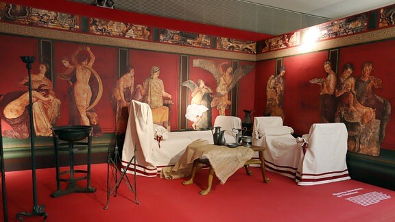 Möbel in einer Ausstellung vor prachtvoll bemalten Wänden