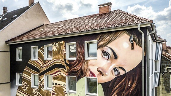 Eine Hauswand in Chemnitz, auf der das Gesicht einer Frau gemalt ist.