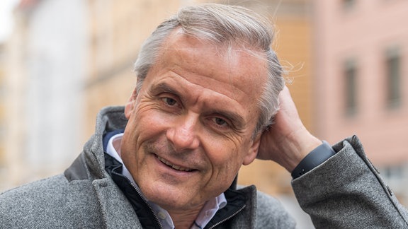 Der Schriftsteller Axel Hacke, ein Mann mit grauen Haaren er trägt einen grauen Mantel 