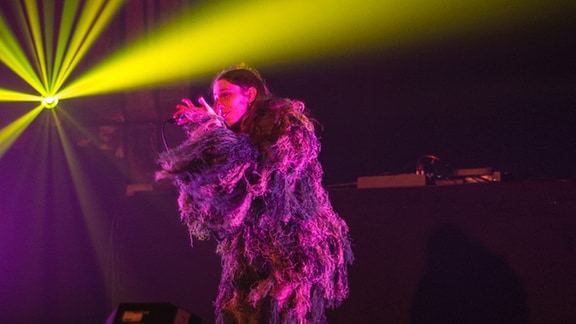 Odete singt in einem Kostüm aus Wollfäden auf der Bühne des UT Connewitz (Re:Balance 2021).