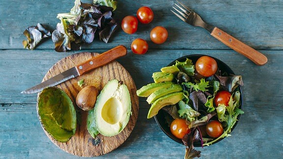 Schüssel und Brett mit Salat und Gemüse