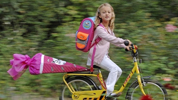 Ein kleines Mädchen mit Schultüte auf dem Fahrrad