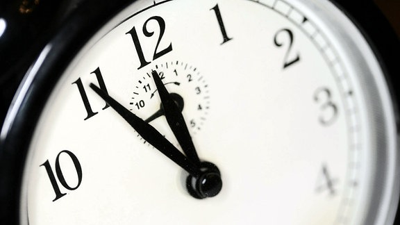 Ein Wecvker zeigt dei uhrzeit vom fünf Minuten vor Mitternacht.