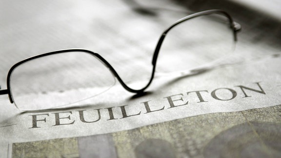 Brille liegt auf dem Feuilleton einer Tageszeitung
