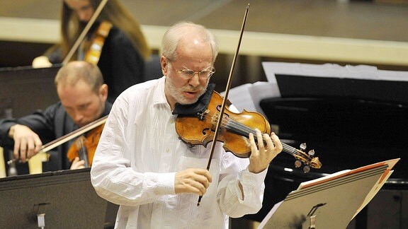 Ein älterer Mann spielt Geige auf einer Bühne
