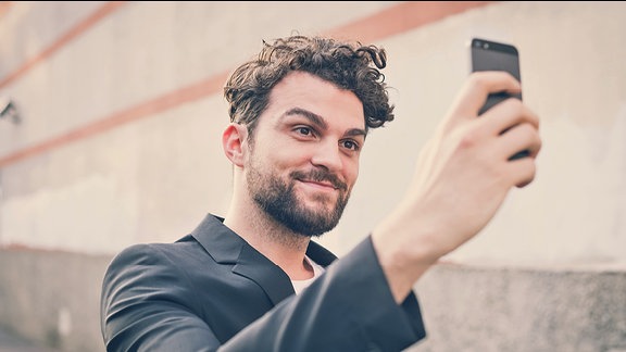 Ein Mann mit einem Smartphone mach ein Selfie