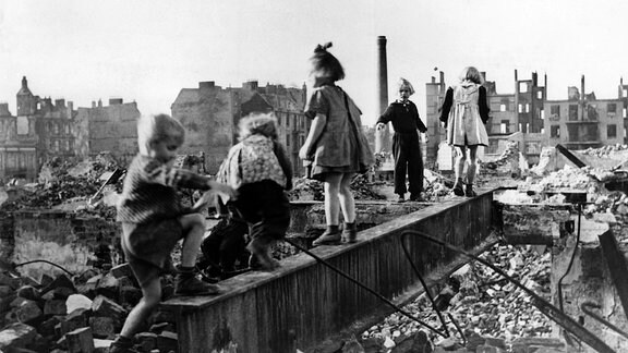 Eine Gruppe Kinder spielt in den Trümmern einer zerstörten Stadt im Deutschland der Nachkriegszeit.