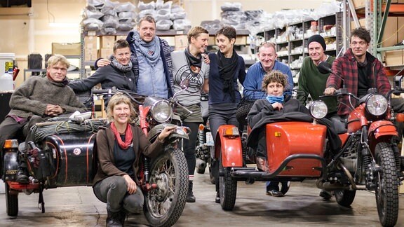 Menschen posieren mit Motorrädern für ein Gruppenfoto