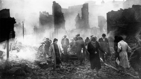 Menschen bewegen sich nach einer Bombardierung im November 1940 durch Gebäudeüberreste in der englischen Stadt Coventry.