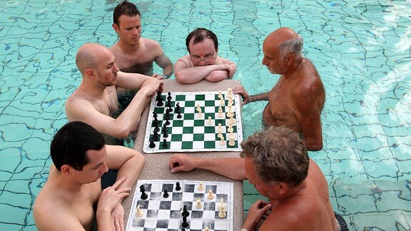 Männer spielen im Aussenbecken eines Thermalbades Schach
