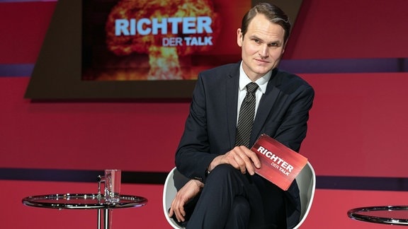Talkmaster Magnus Richter (Fabian Hinrichs) posiert selbstsicher im Studio seiner Talkshow "Richter – Der Talk".