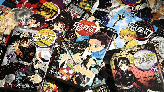 Auf einem Tisch liegen mehrere Ausgaben des Manga Demon Slayer.