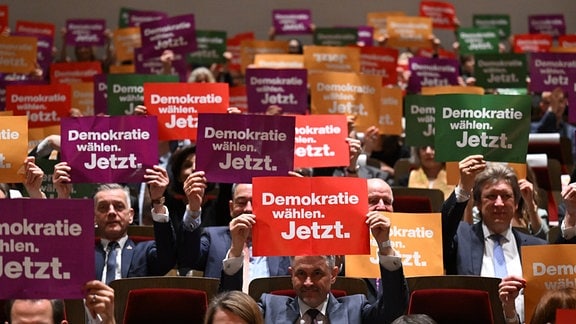 Die Teilnehmer halten Schilder bei einer offiziellen Demokratie-Aktion zur Eröffnung der Leipziger Buchmesse im Gewandhaus.