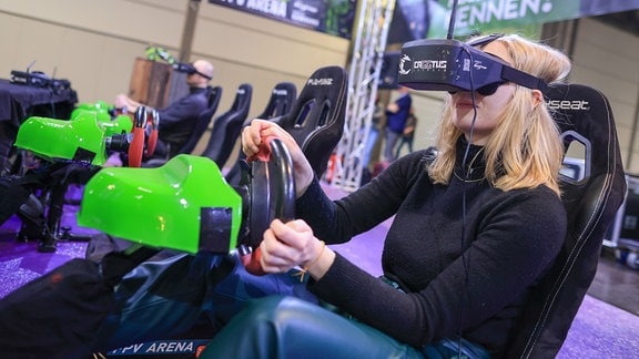 Eine Besucherin des Gamingfestival "CAGGTUS" testet das Fahren und Steuern ferngesteuerter Autos mit einer VR-Brille.