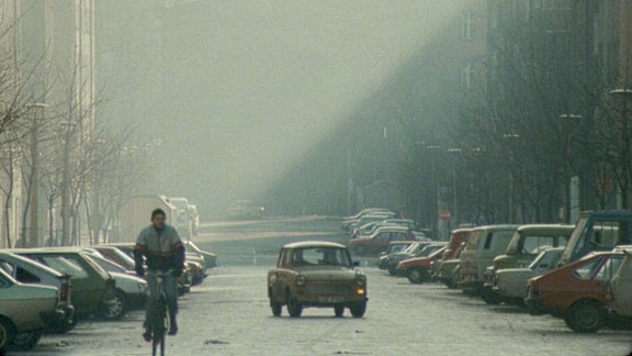 Ein Trabi und ein Fahrradfahrer in Ost-Berlin