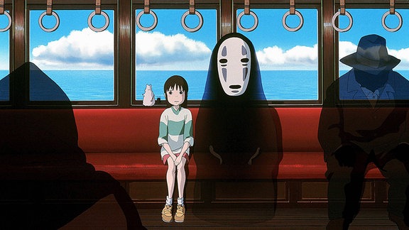 Szene aus einem Manga in dem ein junges Mädchen mit verschiedenen Geistern in einem Straßenbahnwagen sitzt, der an einem Gewässer vorbeifährt