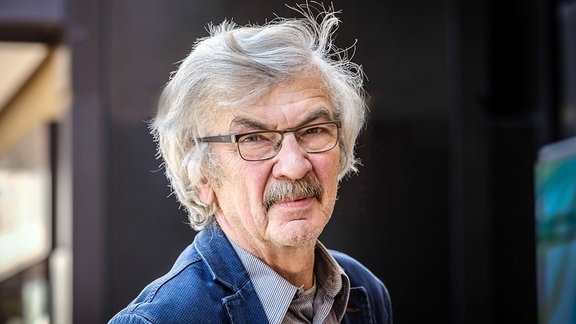 Schriftsteller Christoph Hein: ein Mann mit grauem Haar, Schurrbart und Brille blickt ernst in die Kamera.