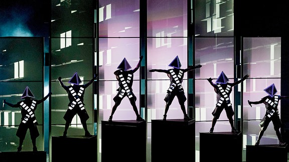 Deichkind: Die Mitglieder der Band tragen Kostüme mit einem Dreieck auf dem Kopf und performen eine Choreografie vor einer LED-Wand auf der Bühne