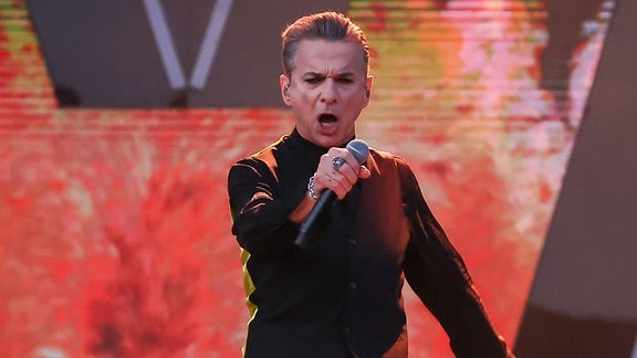 Dave Gahan von Depeche Mode performt auf der Bühne und blickt in die Kamera.