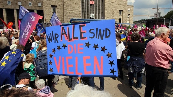Demonstranten halten Plakat mit der Aufschrift "Wir alle sind die Vielen"