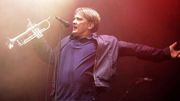 Sven Regener, Sänger von Element of Crime, mit Trompete in der Hand auf einer Bühne 