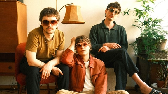 Drei Männer mit Sonnenbrillen in einem Wohnzimmer