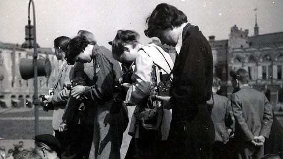 Eine Schwarz-Weiß-Fotografie zeigt mehrere Frauen, mit Kameras in den Händen.  