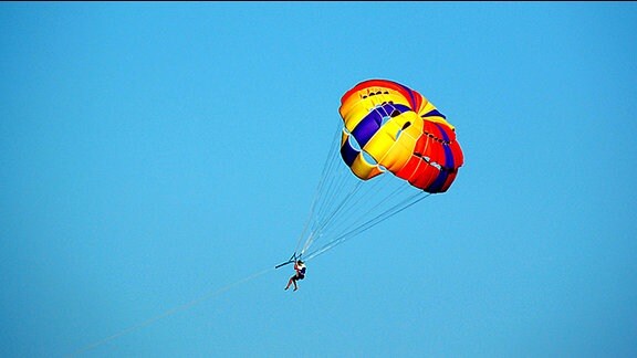 Ein Mann gleitet an einem Fallschirm durch die Luft.