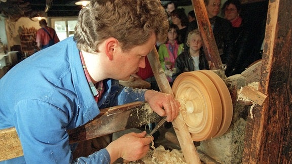 Ein Spielzeugmacher fertigt Holzfiguren beim sogenannten Reifendrehen