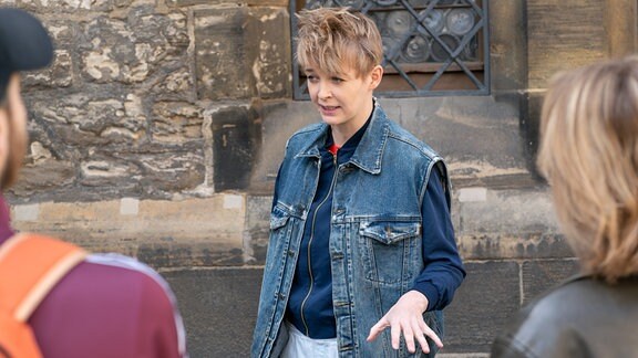 Eine Frau mit kurzen blonden Haaren, sie trägt eine Jeansweste. 
