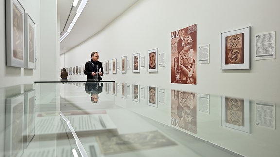 Eine Mann in der Ausstellung "33 Geistesblitze. Antifaschistische Fotomontagen von John Heartfield, 2024 neu gelesen"