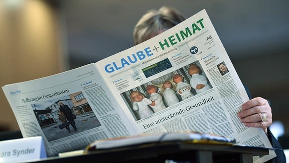 Eine Teilnehmerin der Synode liest die Zeitung "Glaube + Heimat" vor Beginn der Landessynode der Evangelischen Kirche in Mitteldeutschland (EKM). 