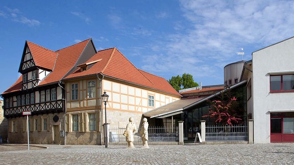 Das Literaturmuseum Gleimhaus in Halberstadt: Ein saniertes Fachwerkhaus steht neben einem modernen Bau mit schrägem Dach, weißer Fassade und roten Fenstern.