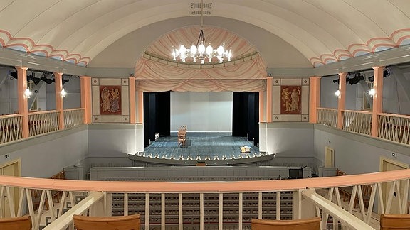 Blick von einer Empore auf einen Theatersaal mit Bühne.