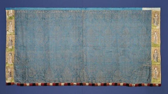 Der blaue venezianische Goldbrokat, ursprünglich vermutlich für ein Pluviale (Chormantel) verwendet, wurde später durch Einfügung von Zwickeln und seitlichen Borten zu einem Antependium (Altarverkleidung) umfunktioniert.