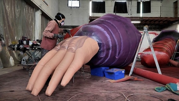 Eine Person arbeitet an der übergroßen, menschlichen Hand.