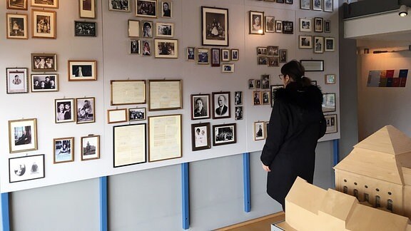 Frau betrachtet Fotografien an einer Wand