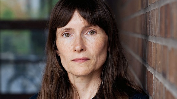Heike Geißler, Leipziger Autorin, posiert an eine Hauswand gelehnt, für ein Foto