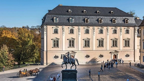 Ein helles barockes Gebäude vor einem Park: Die Herzogin-Anna-Amalia-Bibliothek in Weimar