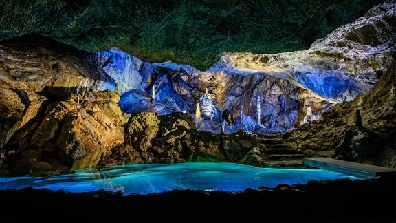 Blick in die Rübeländer Tropfsteinhöhle, die mit blauem Licht punktuell erleuchtet ist