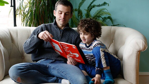 Ein Mann liest einem kleinen Kind aus einem Buch vor