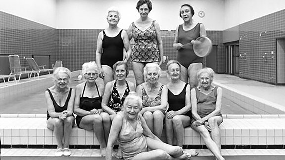 Ein Bild aus der Ausstellung "Joachim Giesel - Menschenbilder Zeitgeschichte", zu sehen sind lauter nette Damen im Badeanzug, die in einem Schwimmbad posieren