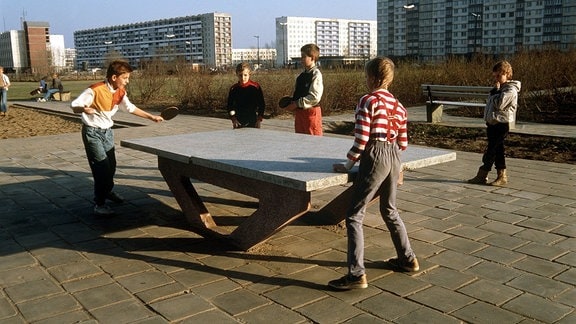 Kinder spielen am 21.02.1990 Tischtennis auf einem Spielplatz in einer Plattenbausiedlung in Halle-Neustadt.