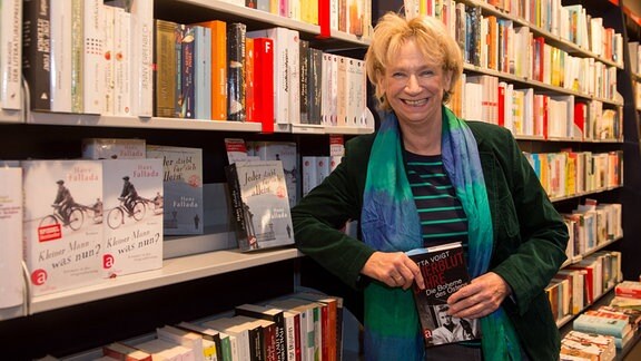Jutta Voigt lehnt auf dem 20. Literaturfestival des Vereins Erfurter Herbstlese an einem Bücherregal.