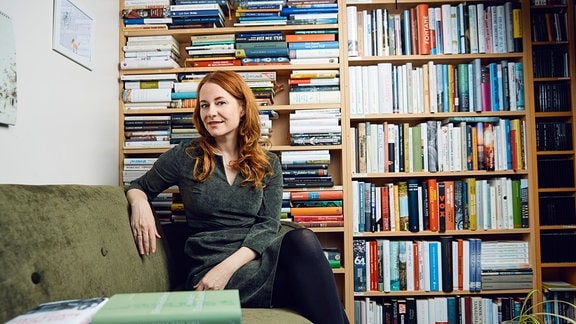 Katrin Schumacher posiert für ein Foto. Im Hintergrund Regale mit Büchern.