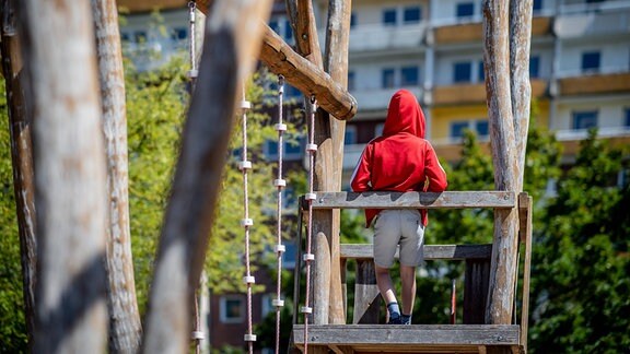 Ein Kind steht auf einem Spielplatz vor einem Plattenbau in Leipzig-Gruenau.