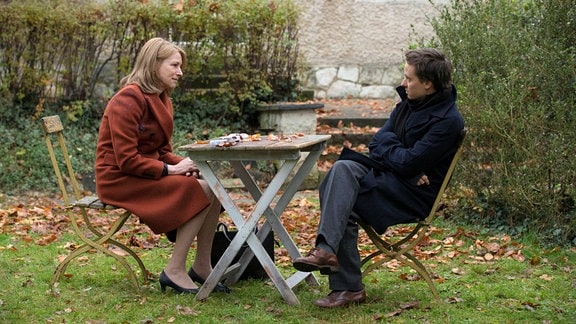 Szene aus dem Film "Lara": Schauspielerin Corinna Harfouch sitzt mit Schauspieler Tom Schilling im Garten an einem Tisch.