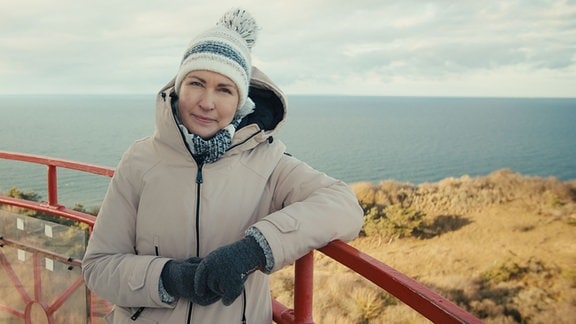 Manuela Schwesig mit Wollmütze und dicker Jacke auf einem Leuchtturm.